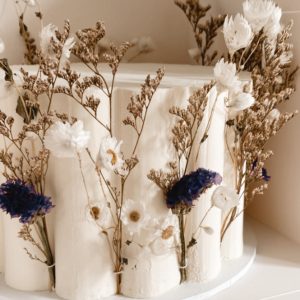 Scalloped white wedding cake with preserved daisies and limonium